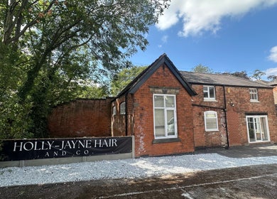 Holly Jayne Hair's charming brick salon exterior in Derby, England, GB amidst lush greenery.