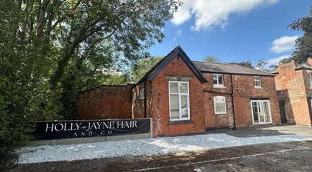 Holly Jayne Hair's charming brick salon exterior in Derby, England, GB amidst lush greenery.