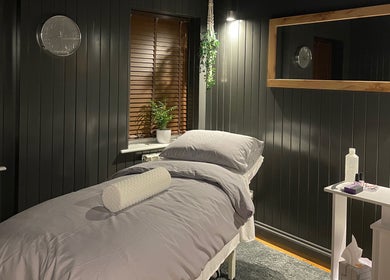 Cozy massage room at Sacred Roots Limited in Guernsey, Vale, GG, with a neatly made bed and serene decor.