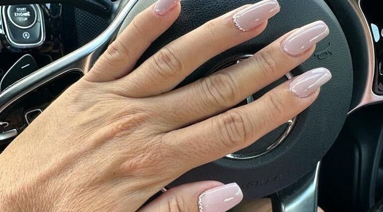 Manicured nails with pink polish from Celini Beauty Salon, Limassol, Limassol, CY on steering wheel.