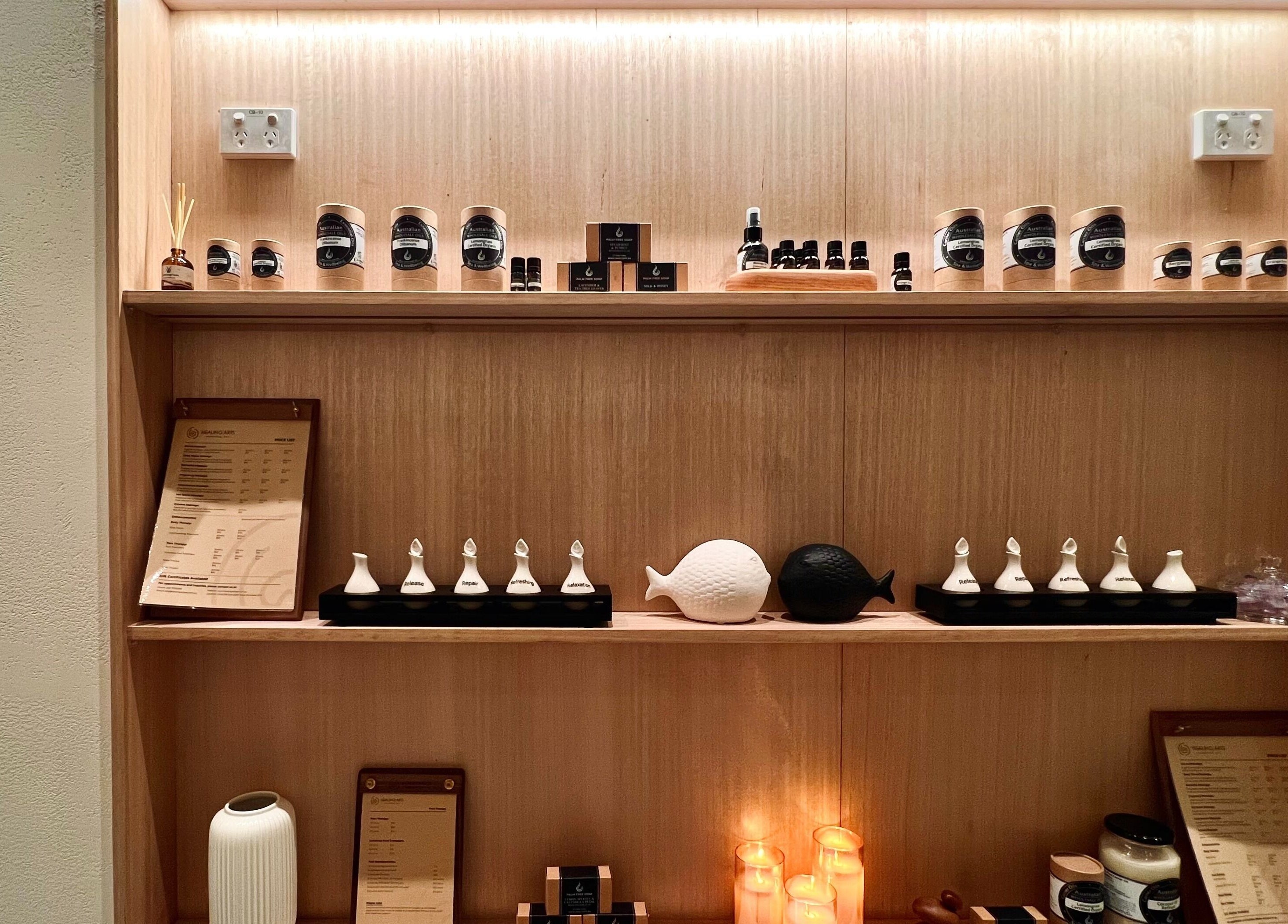 Healing Arts Essential Spa product display in Melbourne, Victoria, AU featuring candles and oils on wooden shelves.