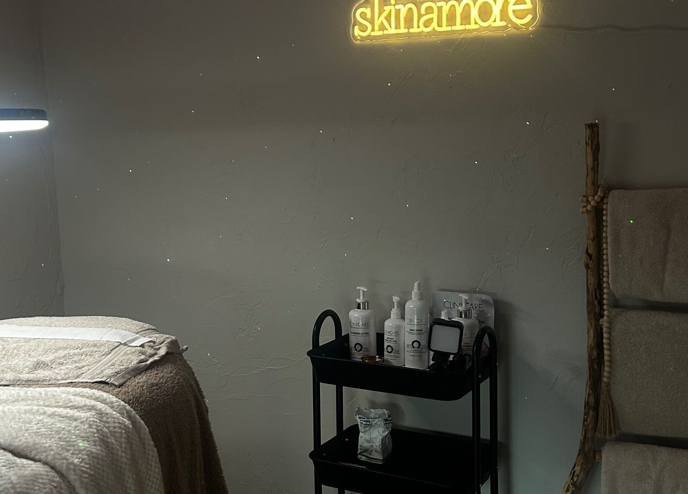 Spa room at Skin Amore in Llangyfelach, Wales, GB with massage bed, towels, and skincare products.