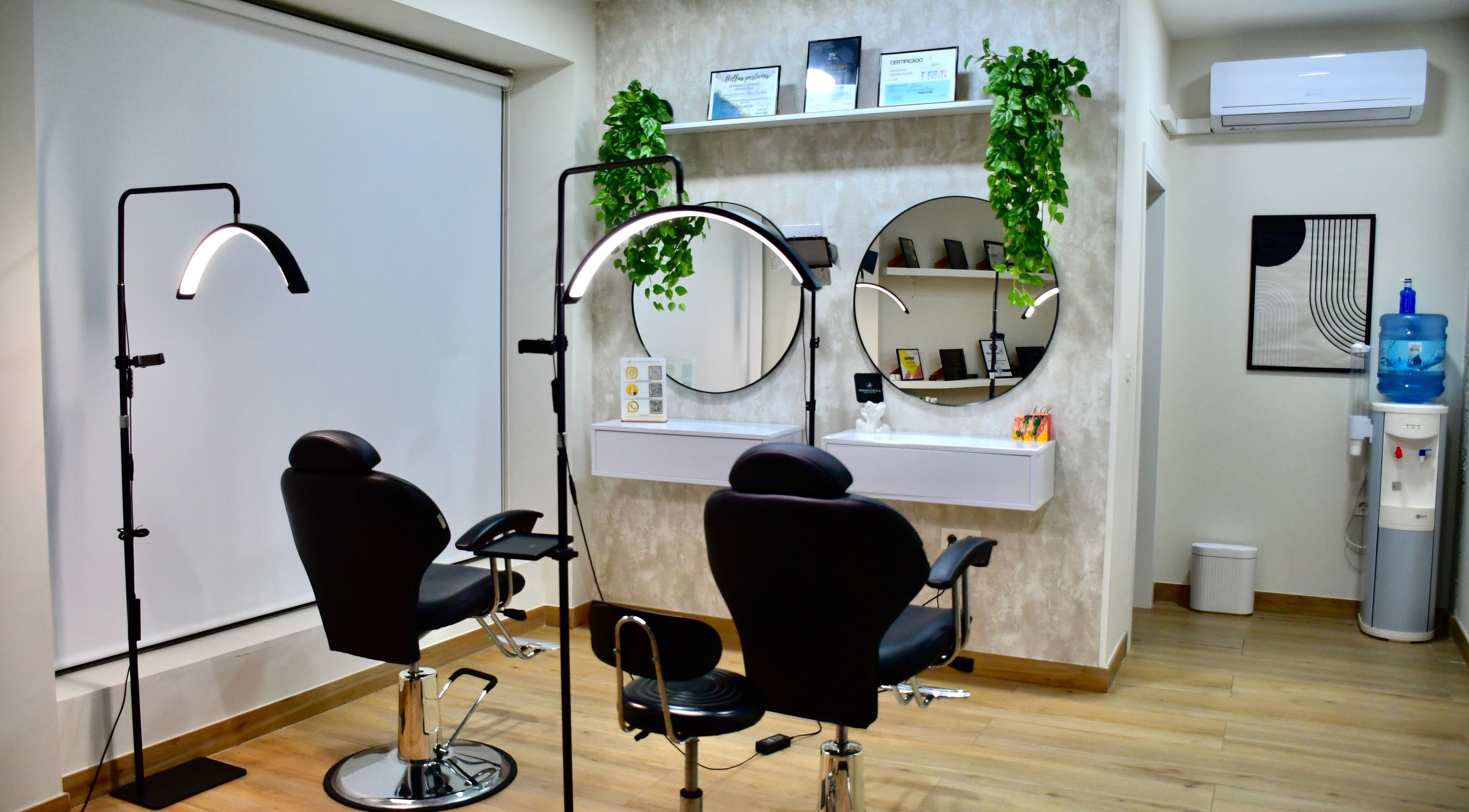 Interior moderno del Adriana Marcela Studio en Adra, Andalucía, ES, con sillas de belleza y espejos circulares.