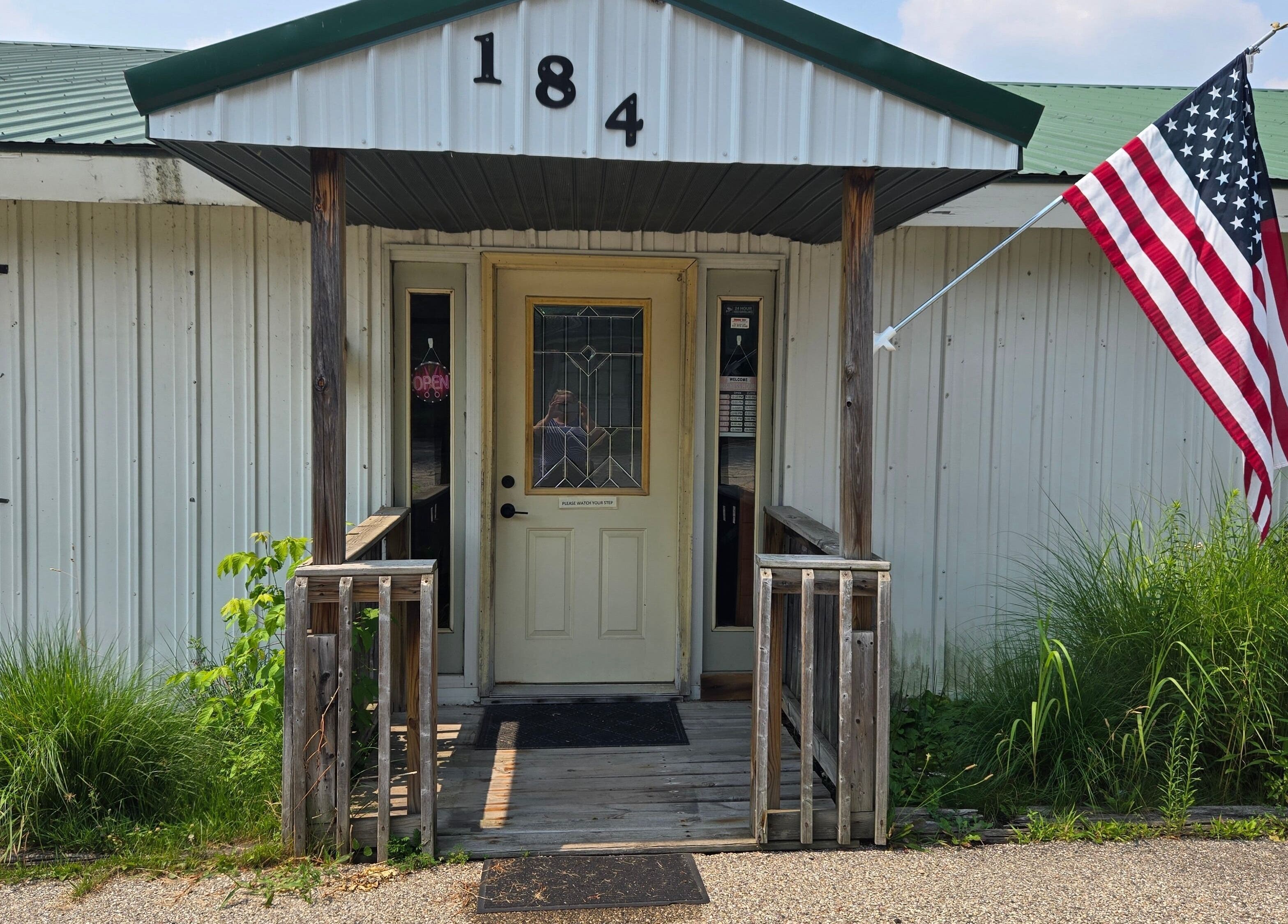 Front entrance of Skin Deep Studio in Remus, Michigan, US, featuring rustic decor and an American flag.
