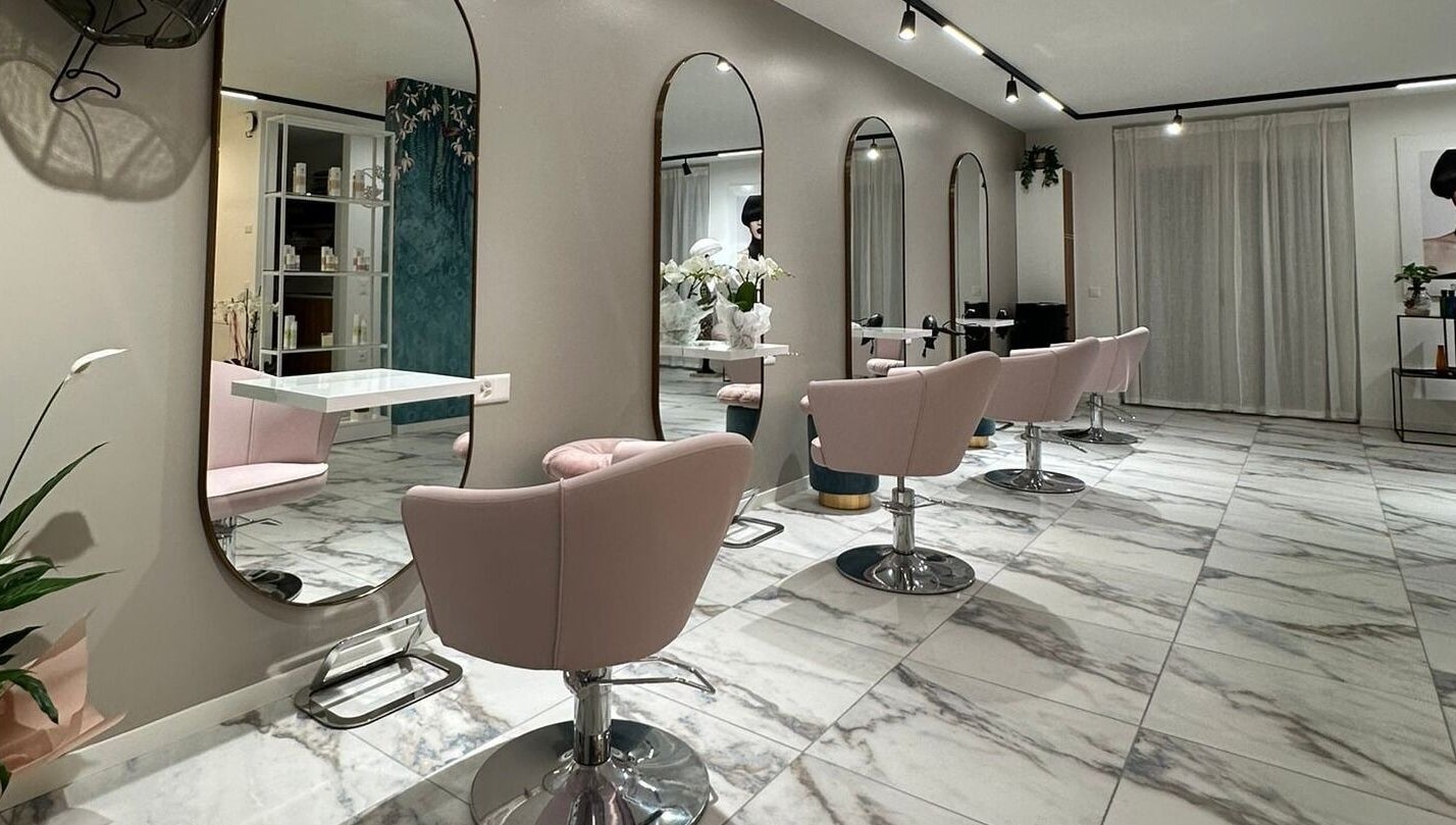Moderno salone di bellezza presso Alchimie SAGL a Mendrisio, Ticino, CH con sedie rosa e specchi eleganti.