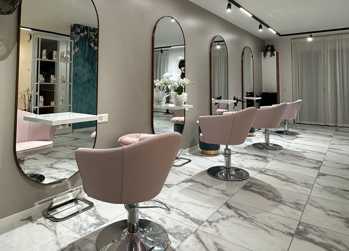 Moderno salone di bellezza presso Alchimie SAGL a Mendrisio, Ticino, CH con sedie rosa e specchi eleganti.
