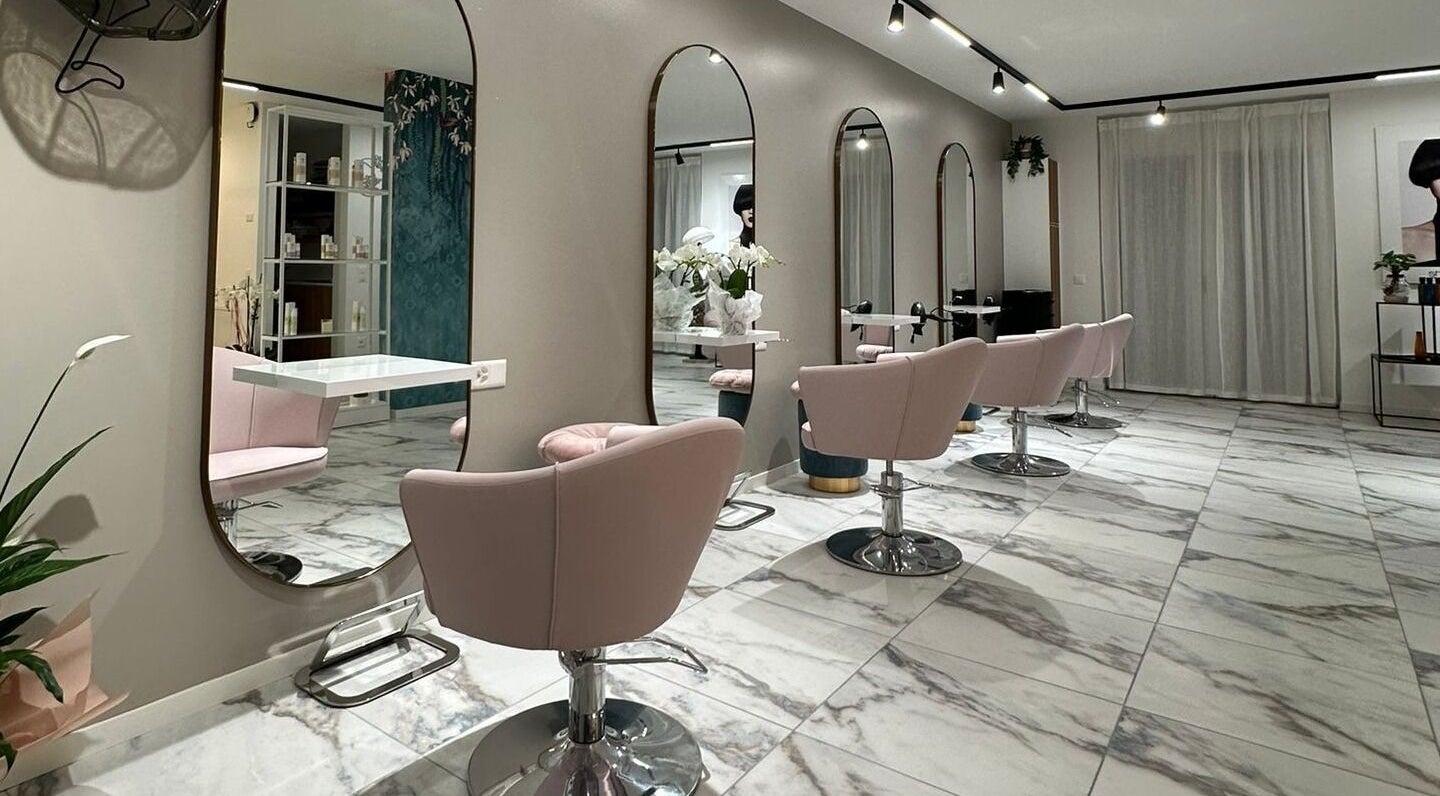 Moderno salone di bellezza presso Alchimie SAGL a Mendrisio, Ticino, CH con sedie rosa e specchi eleganti.