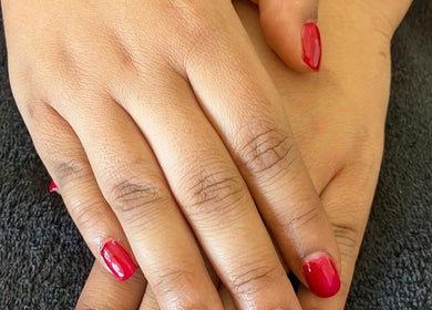 Bright red nails by The A List Beauty Salon in Gqeberha, Eastern Cape, ZA on a soft black towel.