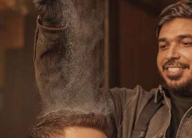 حلاق في DH Barber Shop، عمان، يمارس تقنيات العناية بشعر الزبون باحتراف.
