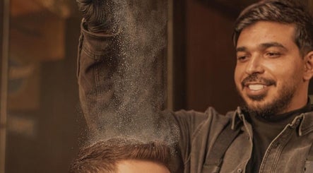 حلاق في DH Barber Shop، عمان، يمارس تقنيات العناية بشعر الزبون باحتراف.