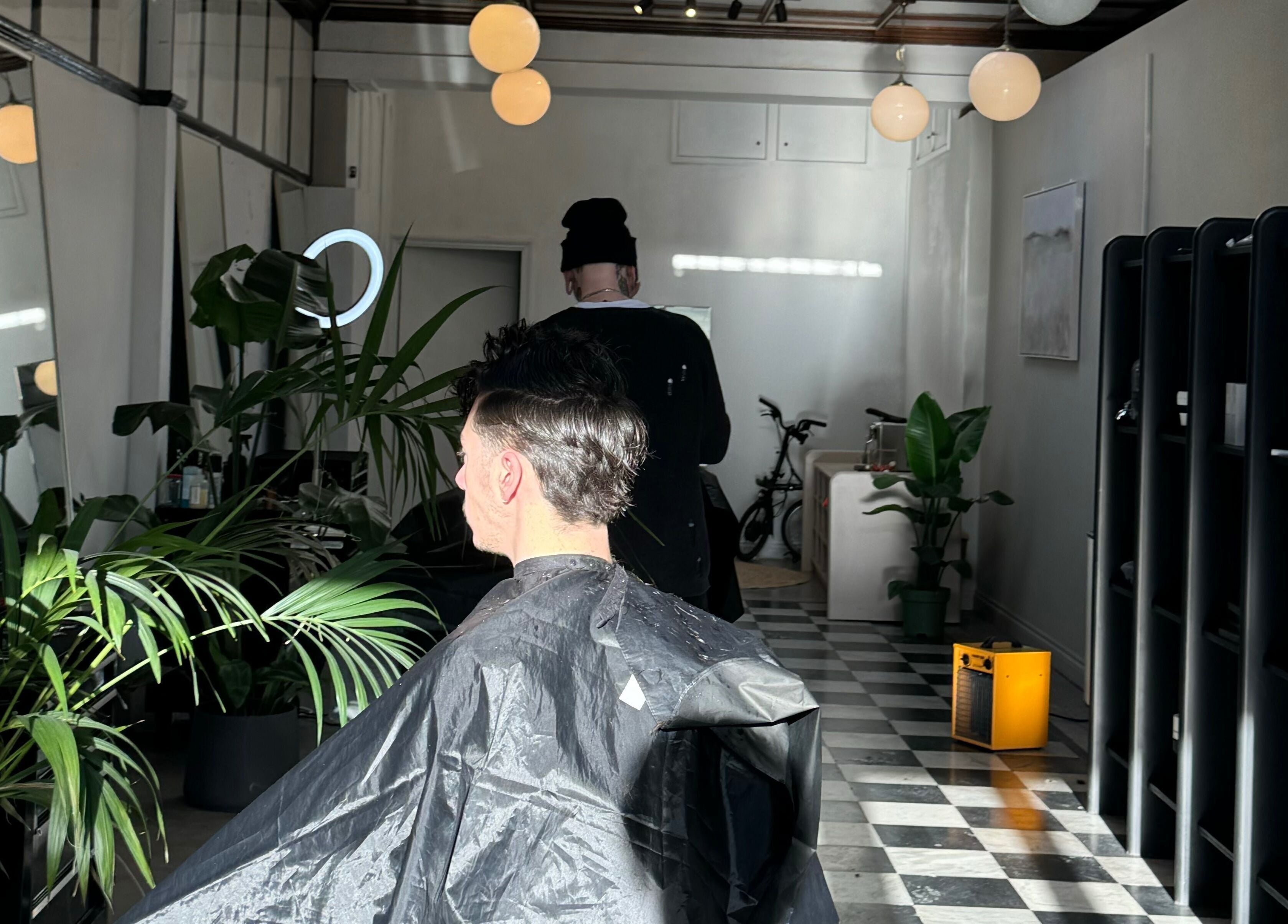 Inside MOAI Barber Studio, London, England, a client in a stylish setting with plants and modern decor.