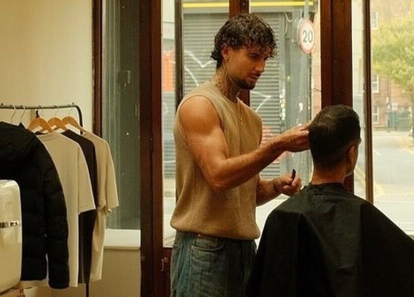Stylist at MOAI Barber Studio in London, England, GB expertly cuts client's hair near window.