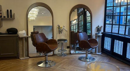 Stylish salon interior with brown chairs at SLICKS Hair Design, Gillingham, England, GB. Modern mirrors and lighting.
