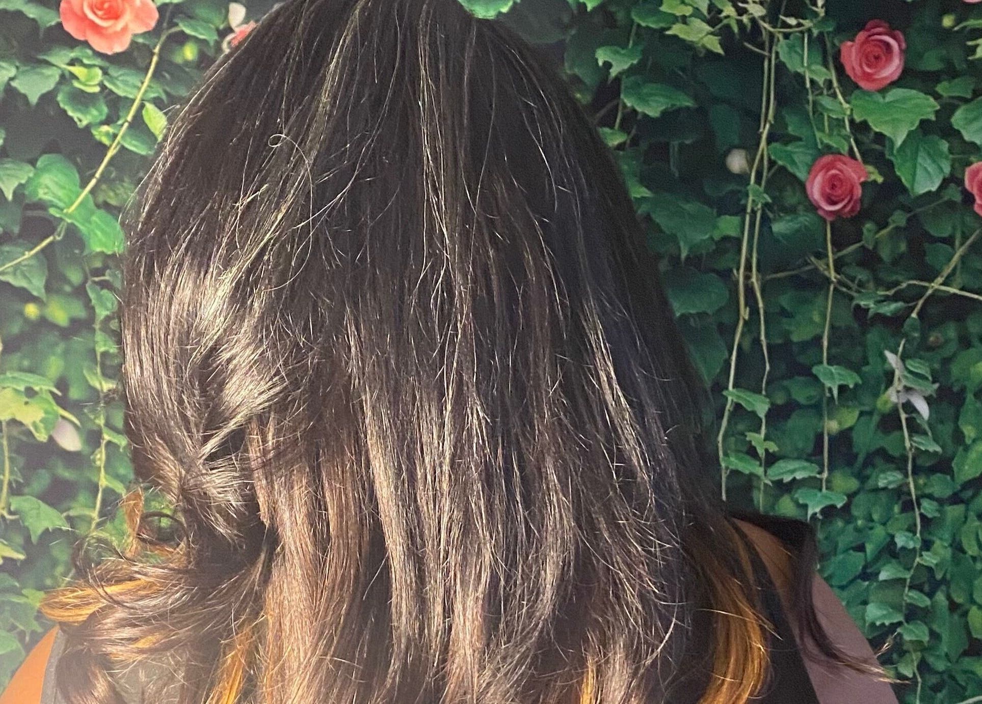 Elegant styled hair at Rich Girlz Hair Studio, Houston, Texas with rose backdrop.