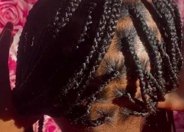 Intricate braided hairstyle at Rich Girlz Hair Studio, Houston, Texas, US, with vibrant rose background.