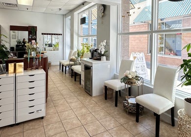 Bright waiting area of Act II Salon in Fairfax, Virginia, US with elegant seating and lush plants.