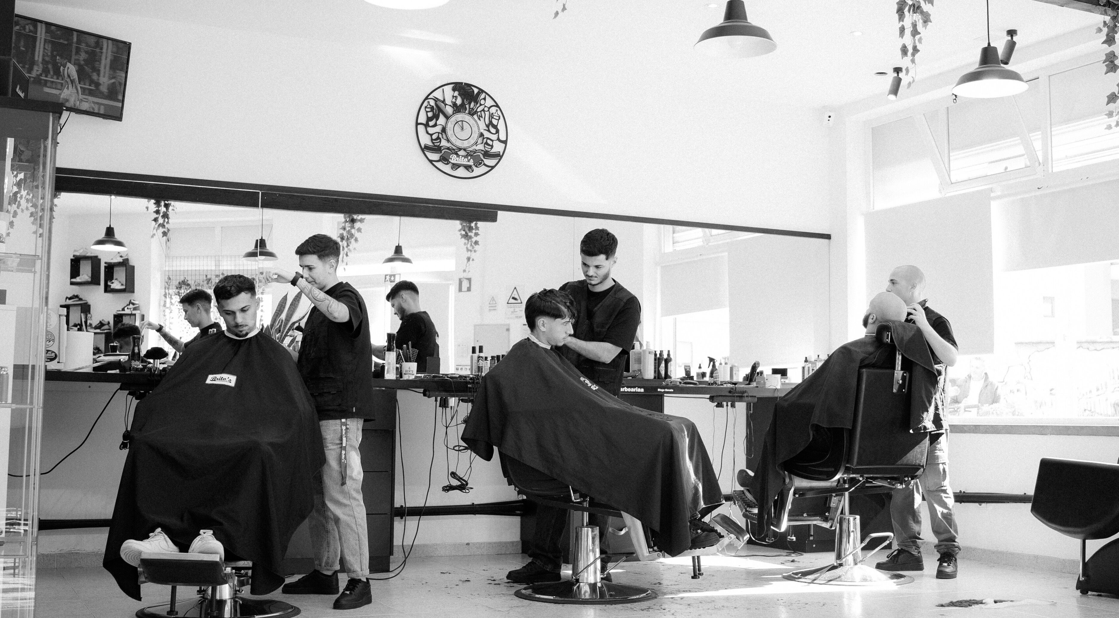 Interior moderno do Brito’s Barbearia em São Brás De Alportel, Faro, PT. Barbeiros atendendo clientes.