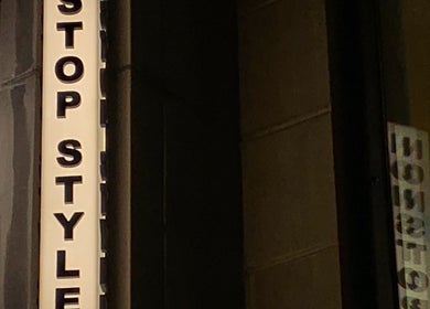 Nonstop Style 33 vertical sign at storefront in New York, New York, US, illuminated warmly at night.