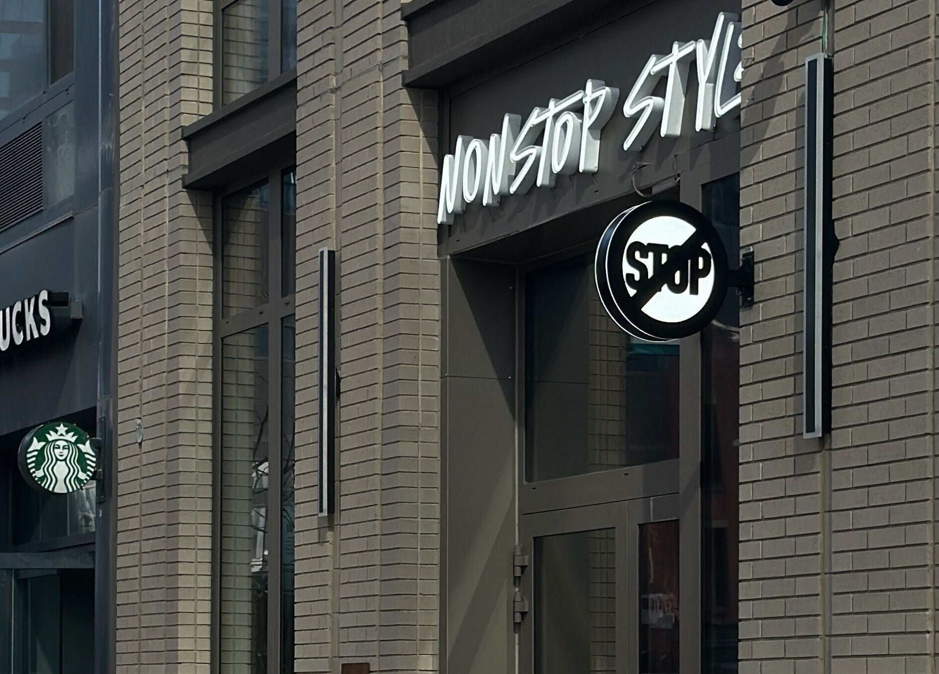 Entrance of Nonstop Style LIC in New York, New York, US, showcasing modern design next to Starbucks.