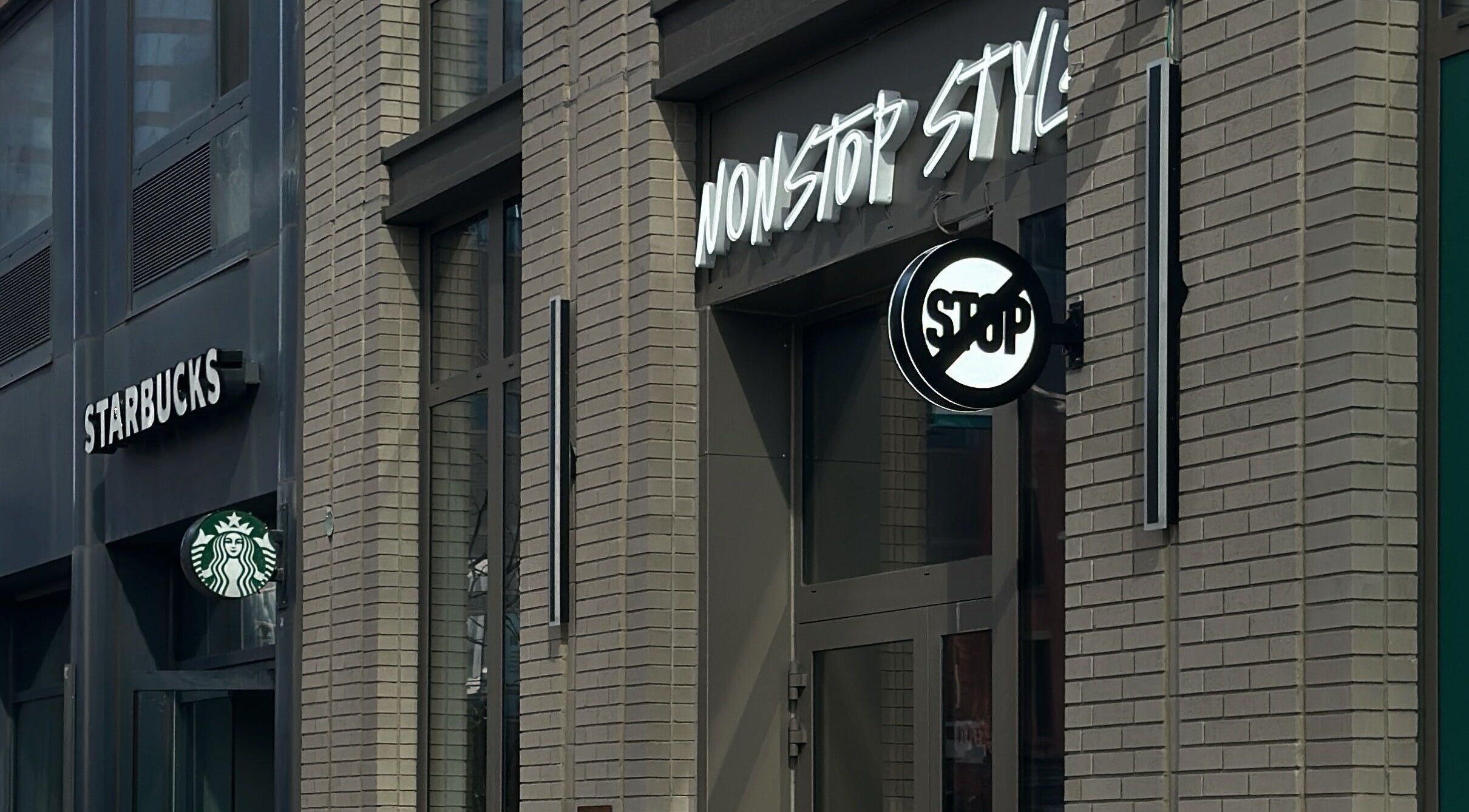 Entrance of Nonstop Style LIC in New York, New York, US, showcasing modern design next to Starbucks.