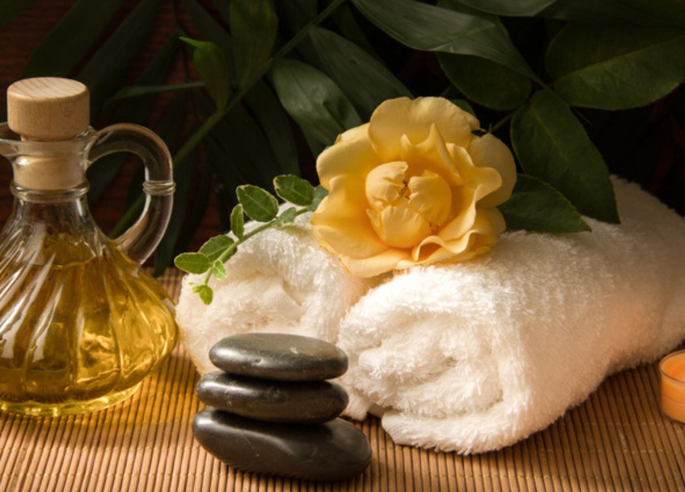 Calming spa essentials at iRis, Taunggyi, Shan State, MM, showcasing towels, oil, stones, and a candle.