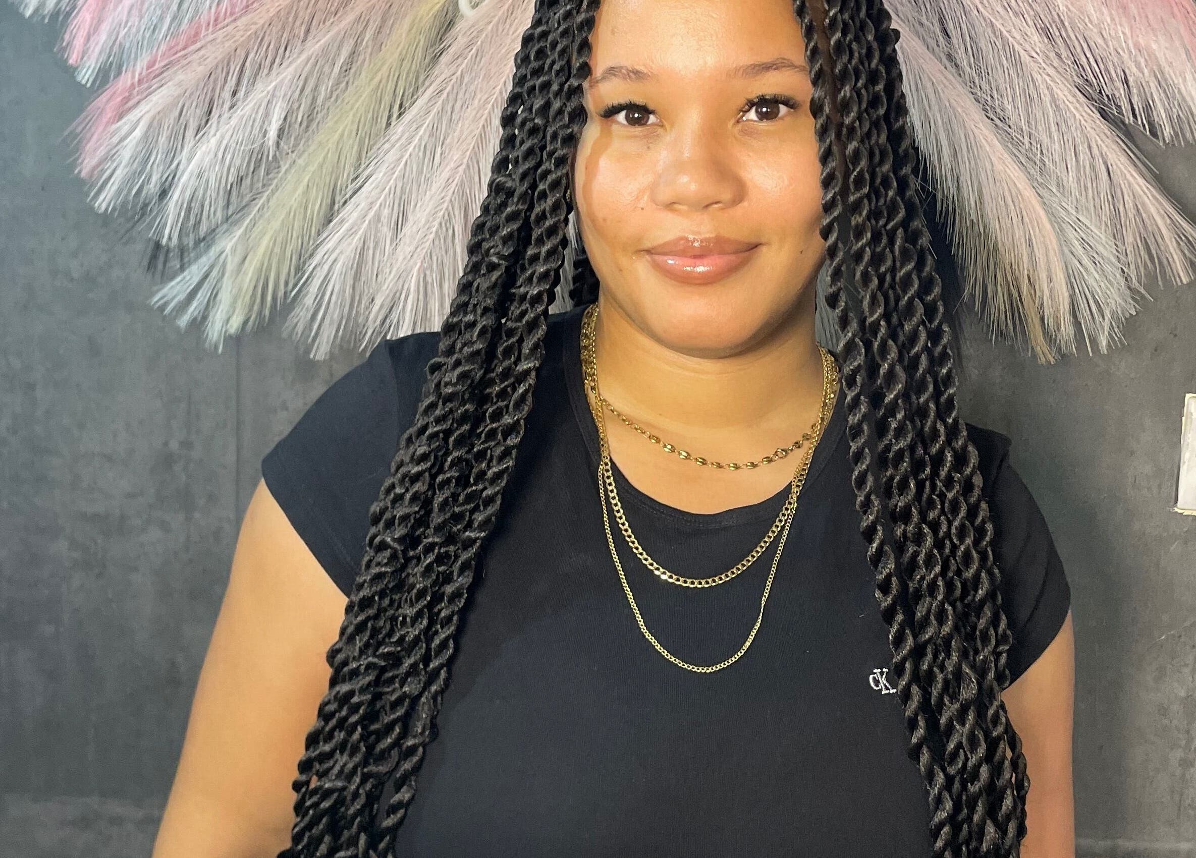 Smiling woman with intricate braids at Braided by Kie, Roseau, DM.