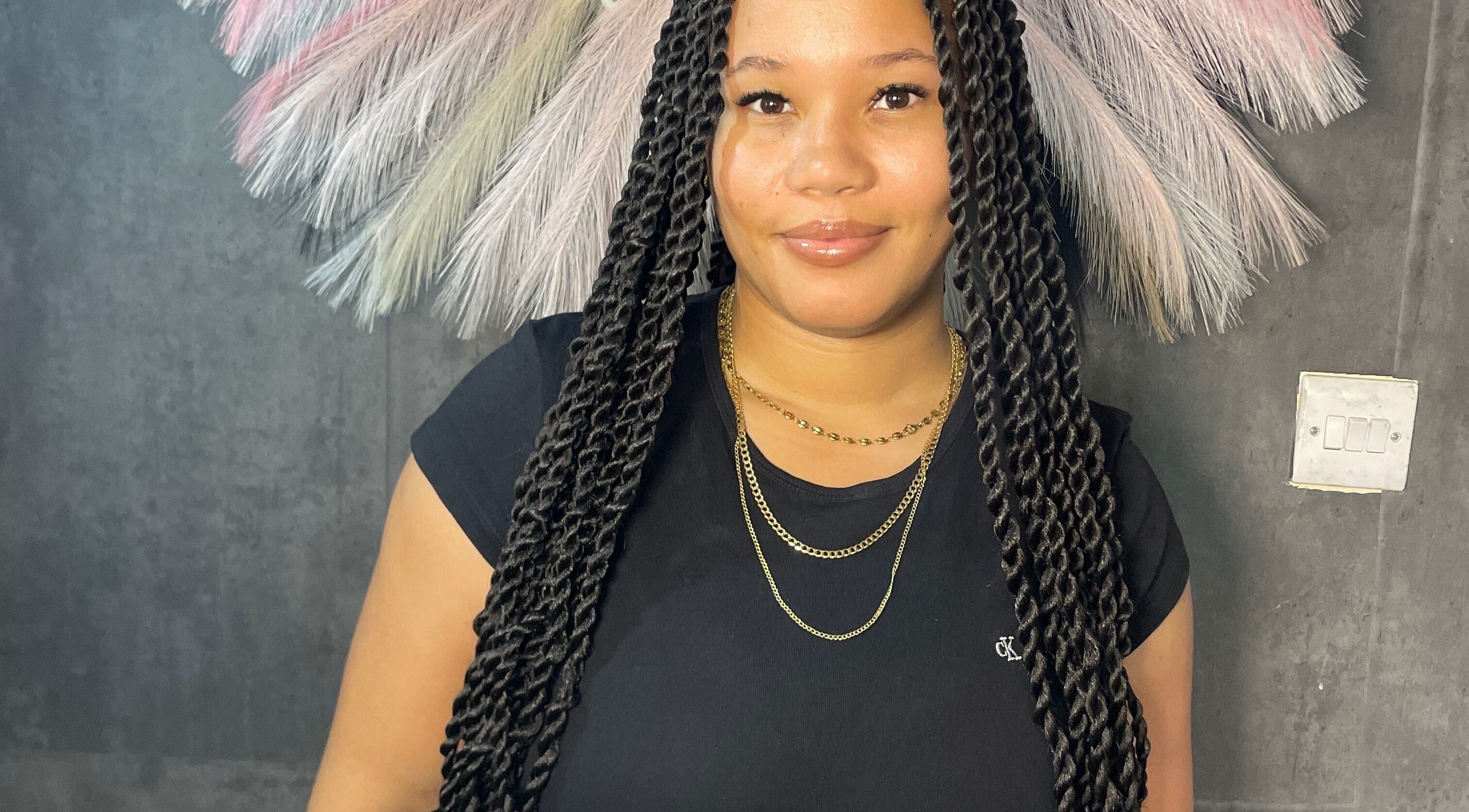 Smiling woman with intricate braids at Braided by Kie, Roseau, DM.