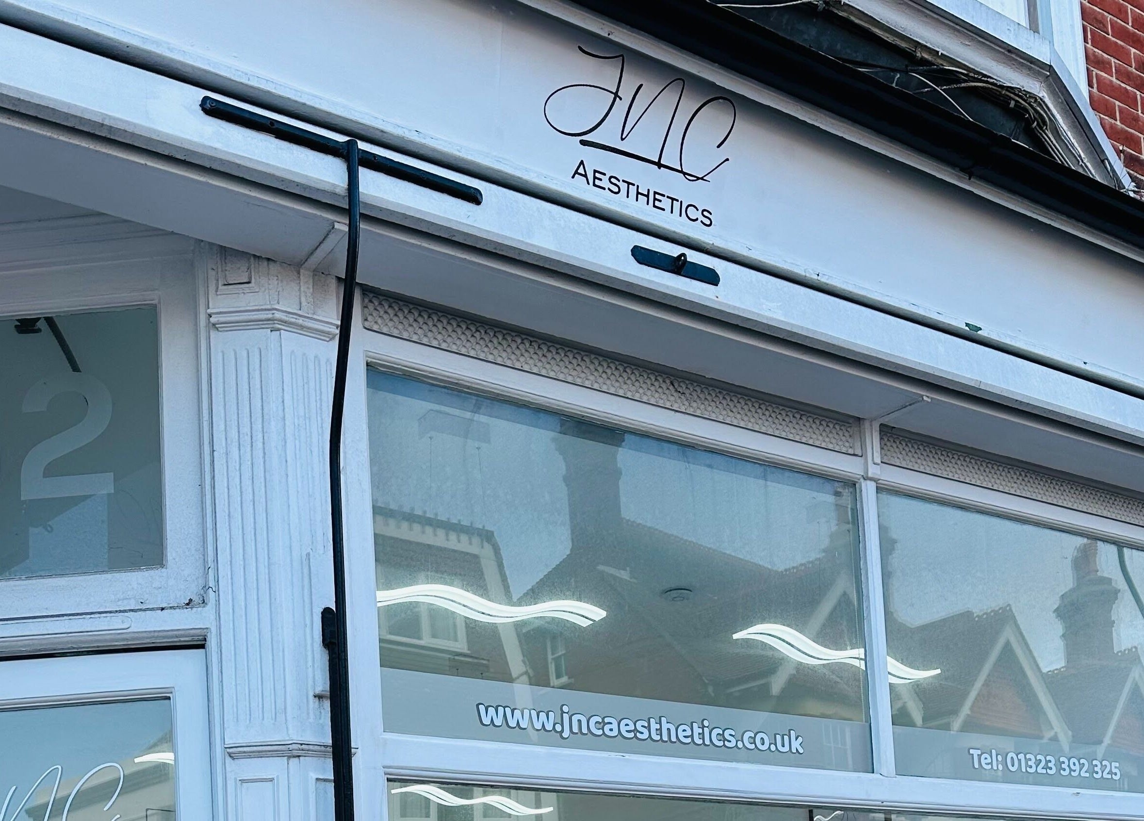 Chic entrance of Jnc Aesthetics on Eastbourne street in England, showcasing a modern facade.