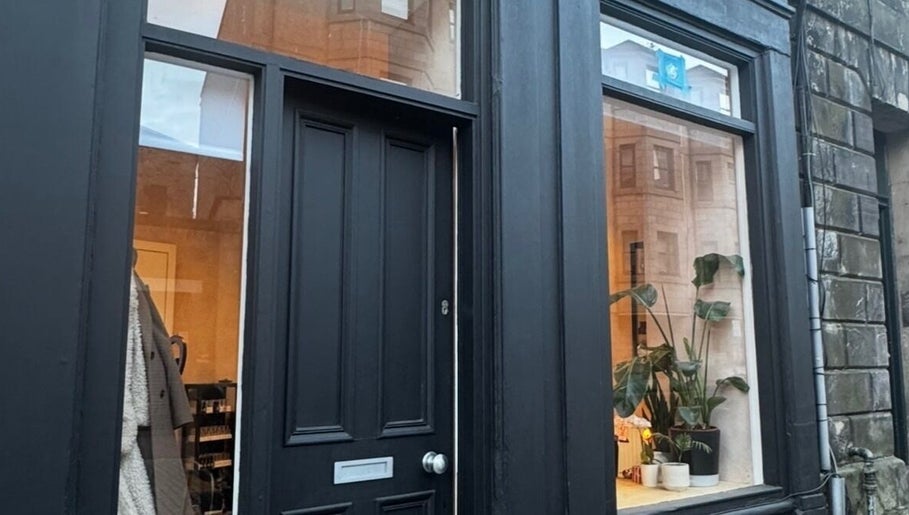 Charming black storefront of Preen in Edinburgh, Scotland, GB with plants in window.