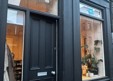 Charming black storefront of Preen in Edinburgh, Scotland, GB with plants in window.