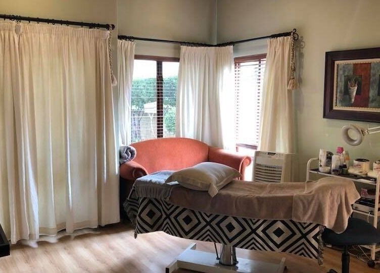 Cozy treatment room at Aesthetics by Des in Cambridge, Waikato, NZ featuring a plush couch and massage bed.