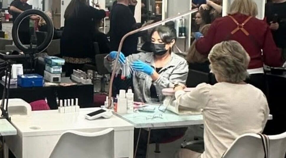 Nail artist working at Nails by Donya in Clarkston, Scotland, GB, providing manicure services in a vibrant salon.