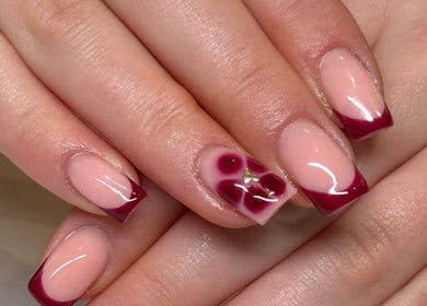 Stylish manicure at Beauty by Em, Clowne, England, GB featuring glossy burgundy tips and floral accent.