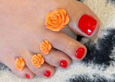 Vibrant red toenails with floral decor at Beauty by Em, Clowne, England, GB.