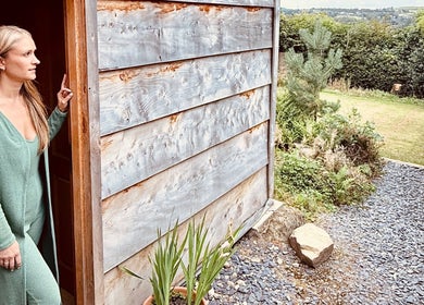 Woman at Cedar Cabin Therapies' entrance, Holmfirth, England, surrounded by nature and serenity.