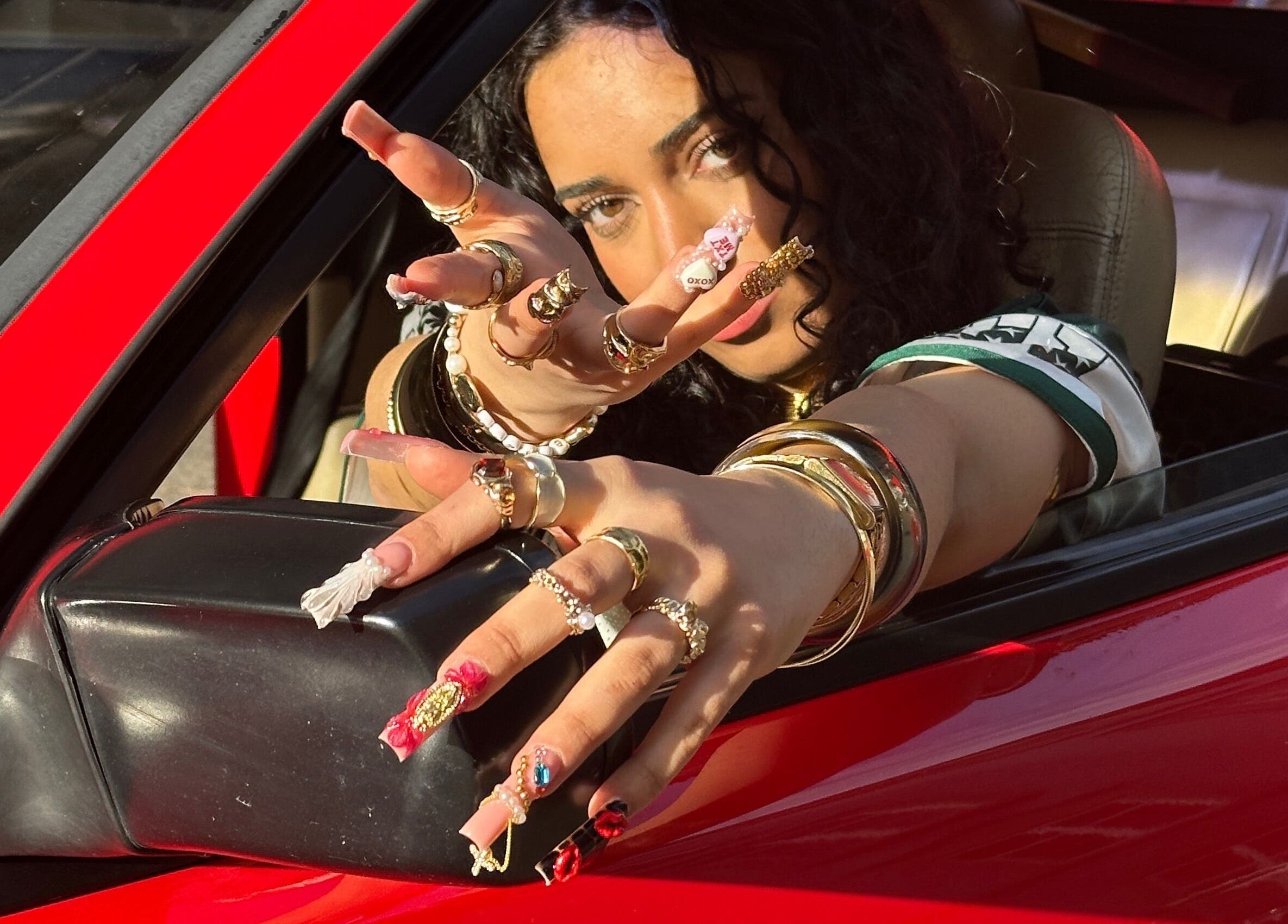 Frau mit kunstvollen Nägeln zeigt Schmuck durch Autofenster bei Babe Cosmetics, Basel, Basel-stadt, CH.