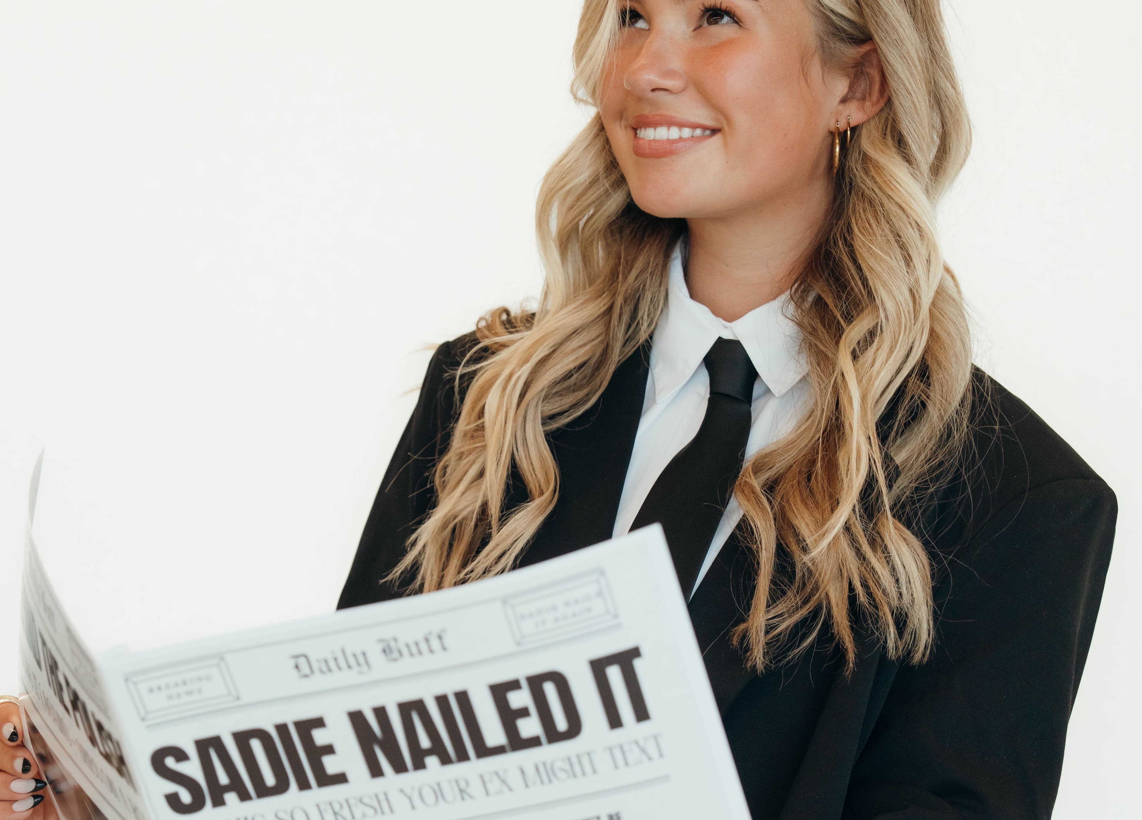Smiling person in a suit reading newspaper at Sadie Nailed It, Pleasant Grove, Utah, US.