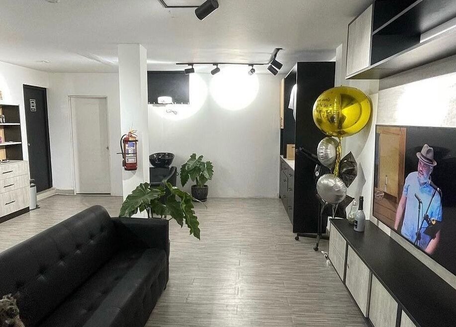 Interior moderno de Melo Barber Studio San Luis, Provincia De Lima, PE, con sofá negro y decoración elegante.