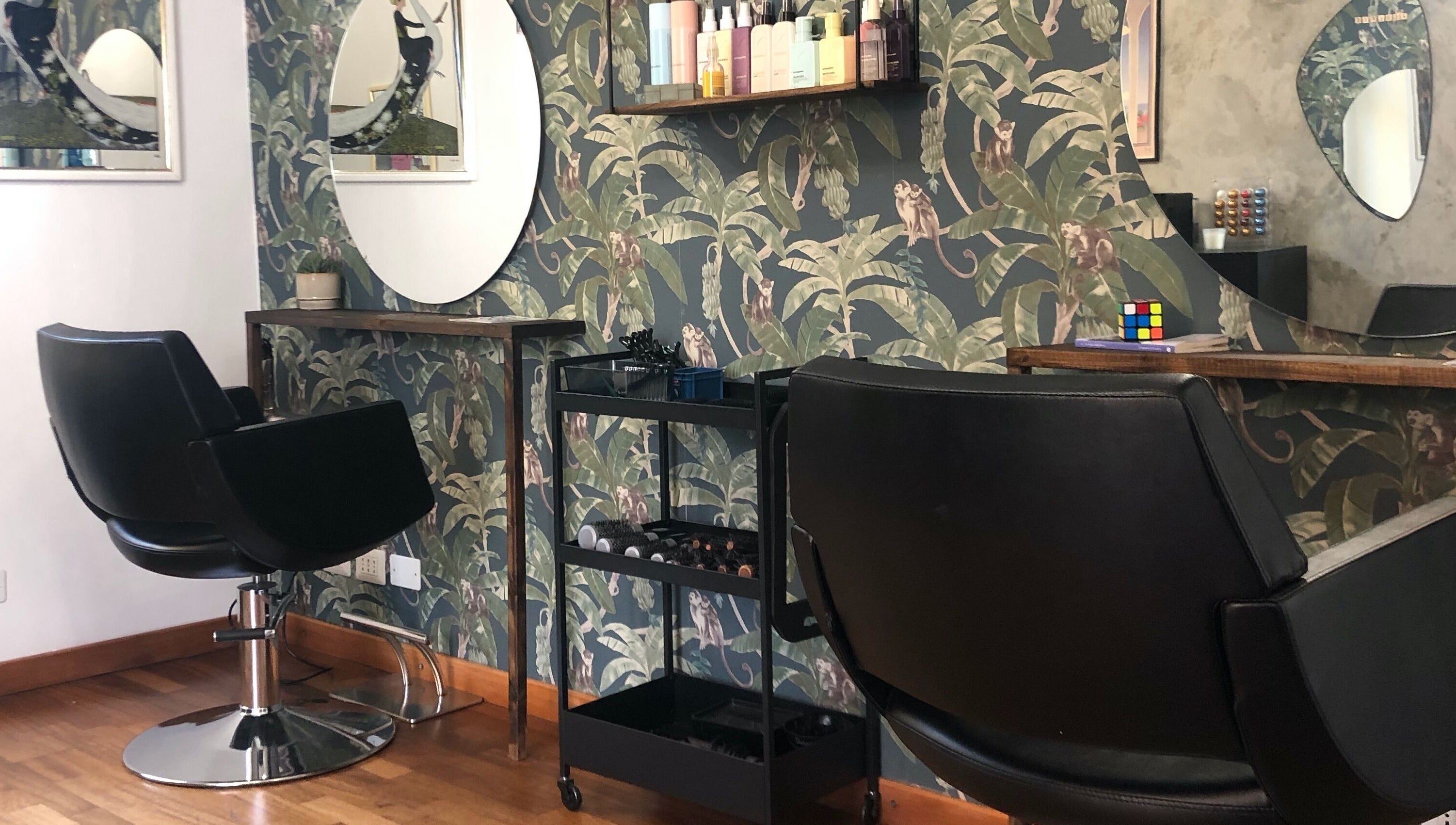 Interno di Jumies Hairsalon ad Arona, Piemonte, IT con poltrona nera e specchio ovale.