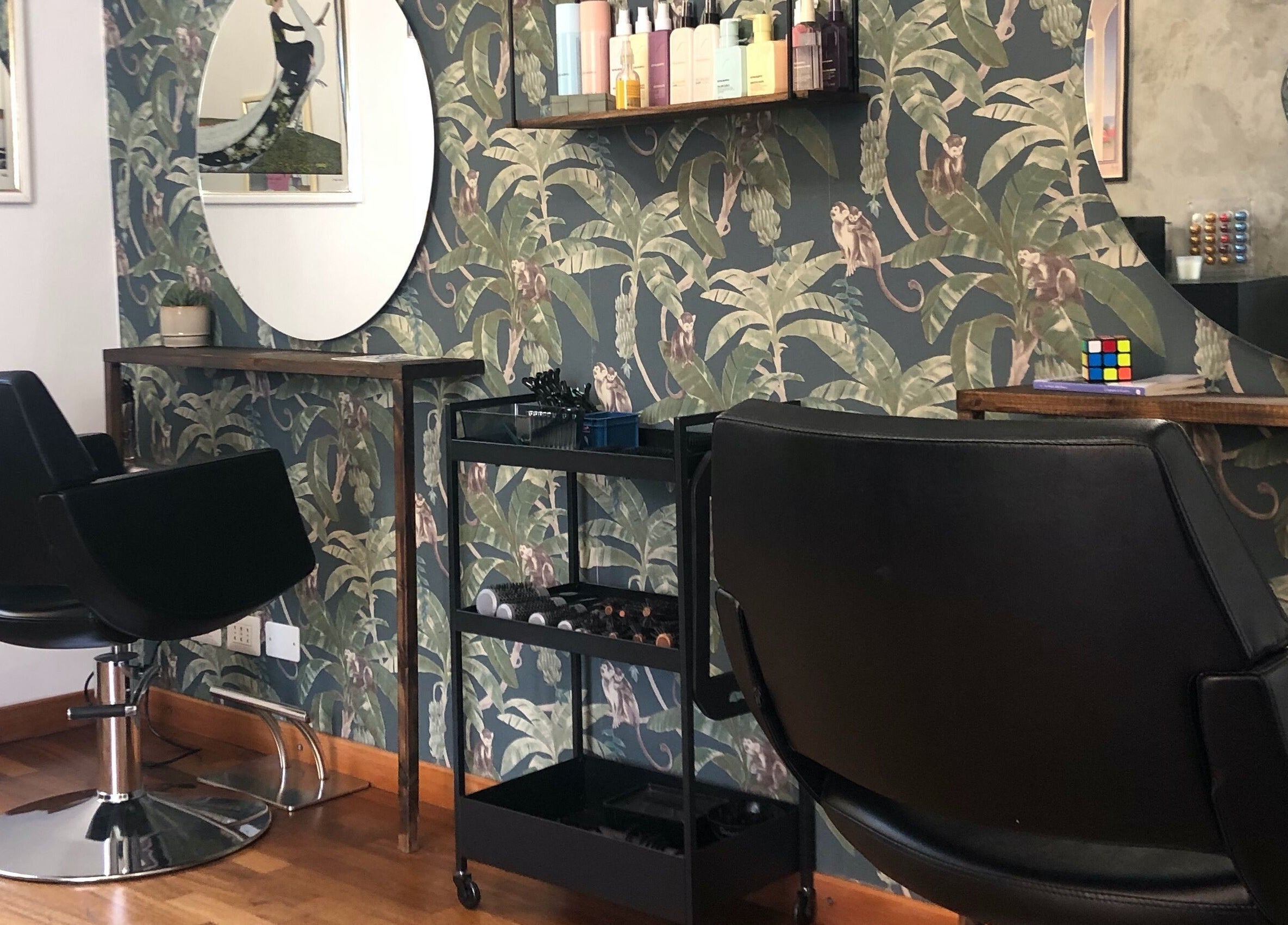 Interno di Jumies Hairsalon ad Arona, Piemonte, IT con poltrona nera e specchio ovale.