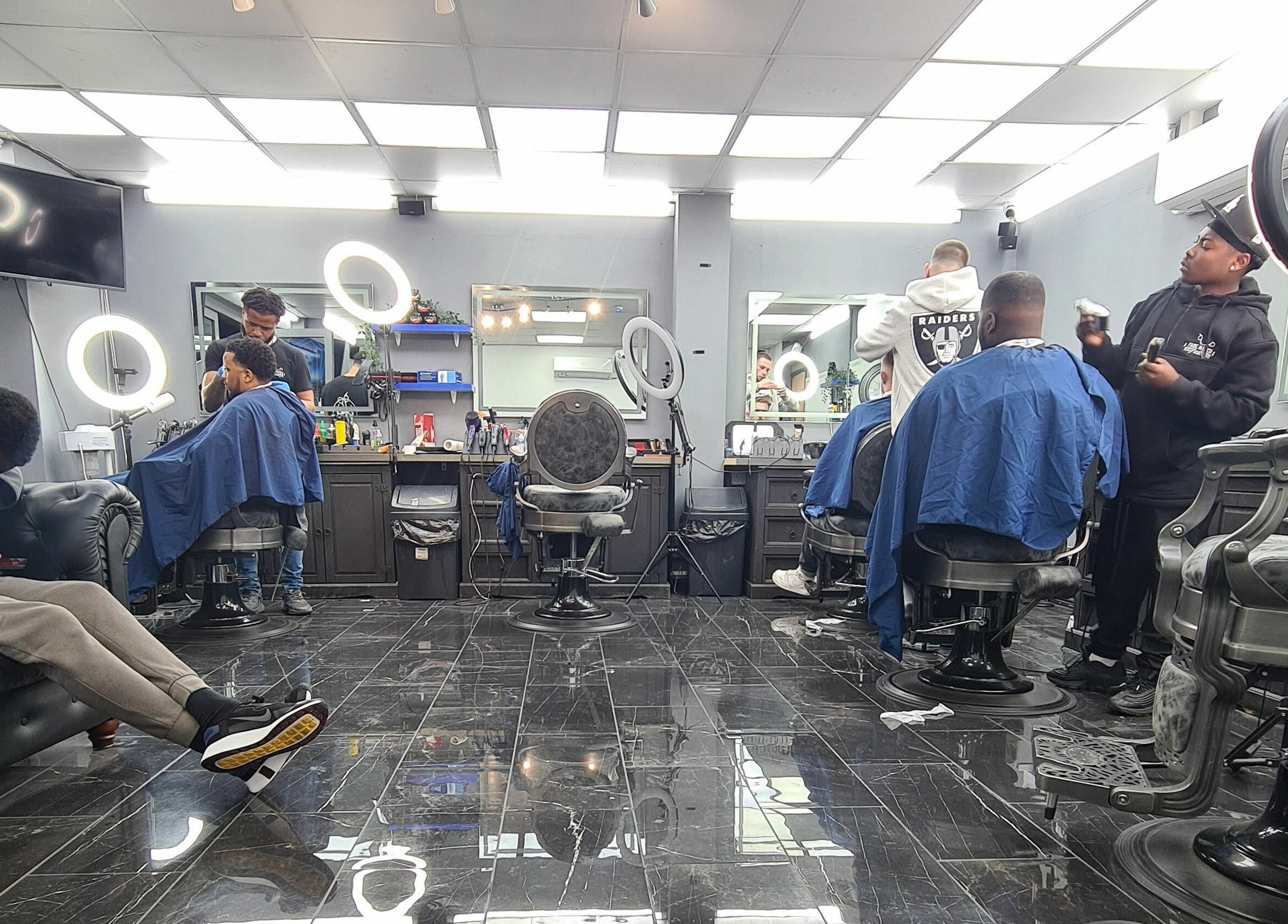 Professional hair stylists working at Fade Matics, Dagenham, England, GB, with modern chairs and lighting.