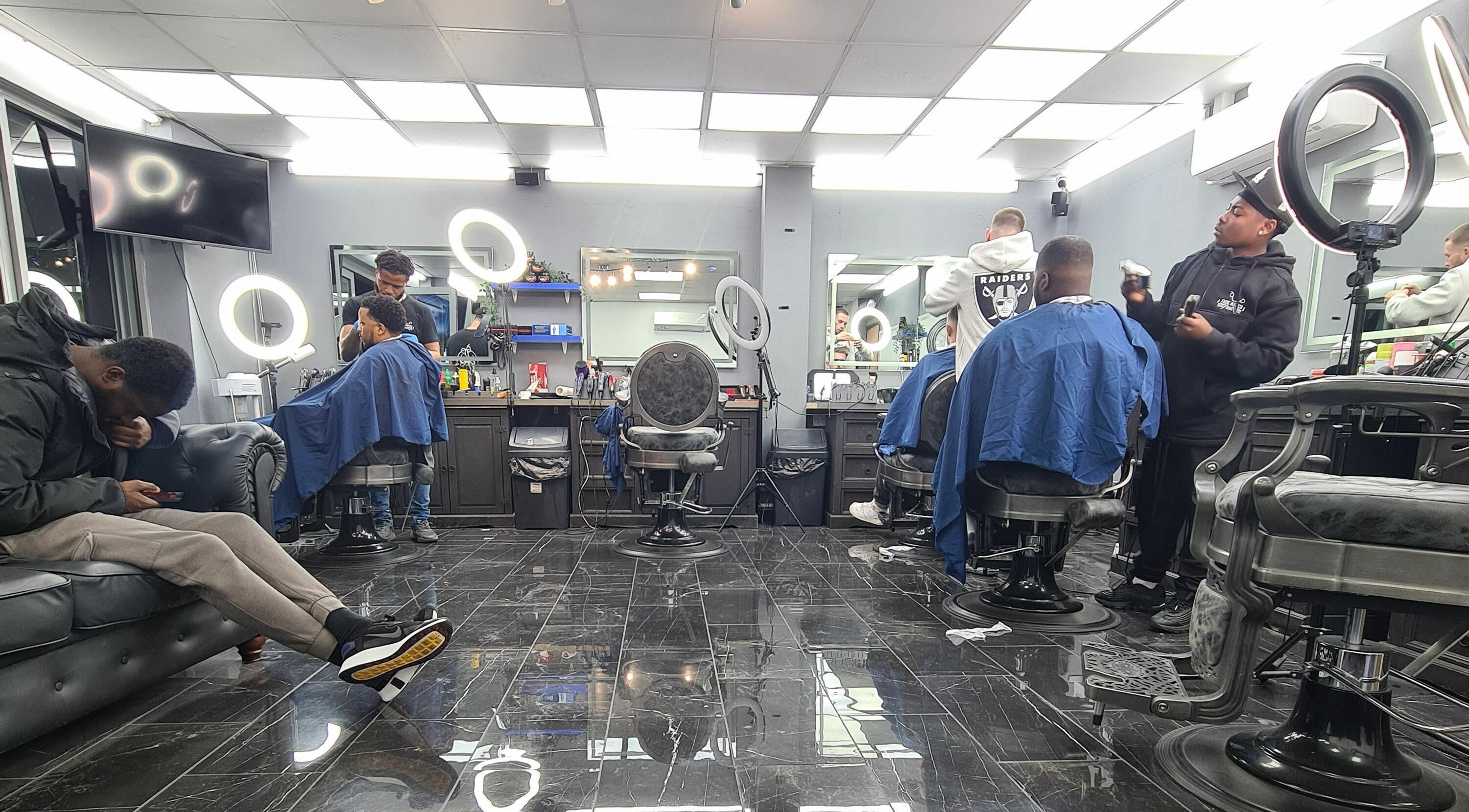 Professional hair stylists working at Fade Matics, Dagenham, England, GB, with modern chairs and lighting.