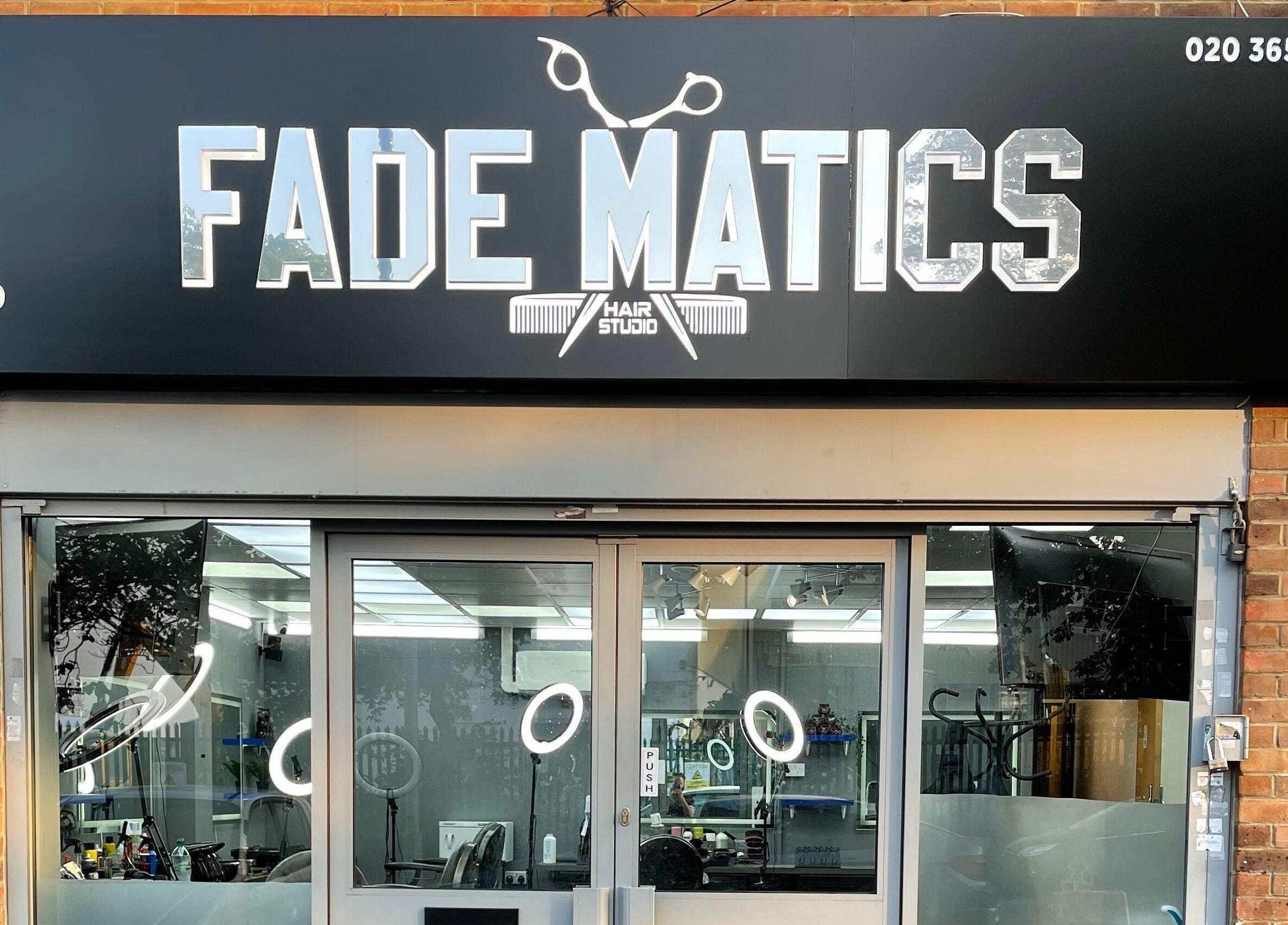 Entrance of Fade Matics hair studio in Dagenham, England, GB with modern signage and glass doors.
