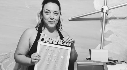 Femme souriante tenant un panneau 'Bonheur' à l'Alchimie de la Beauté, Montréal, Québec, CA.