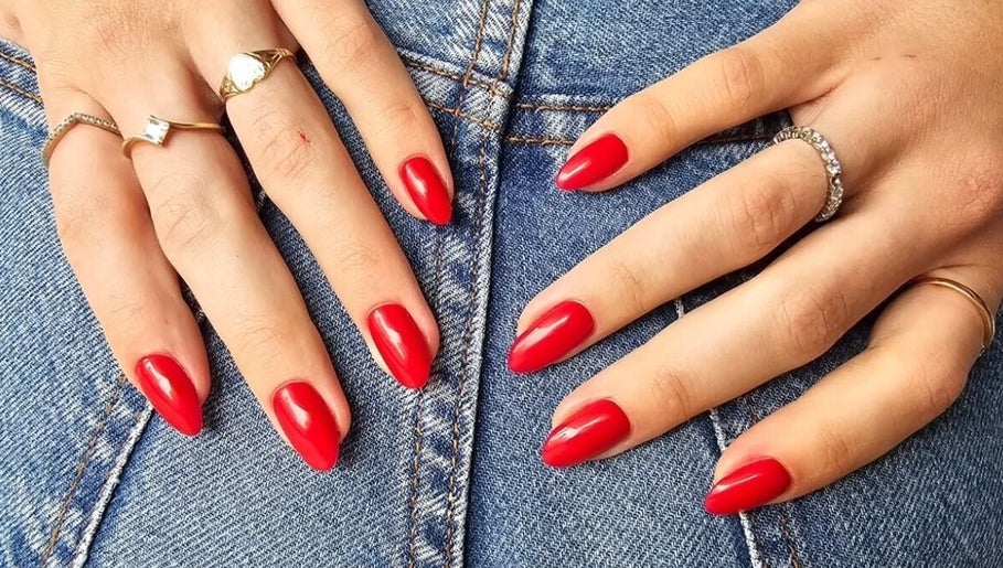 Red manicured nails with rings at GELuxe Nail Studio, Dapto, New South Wales, AU.