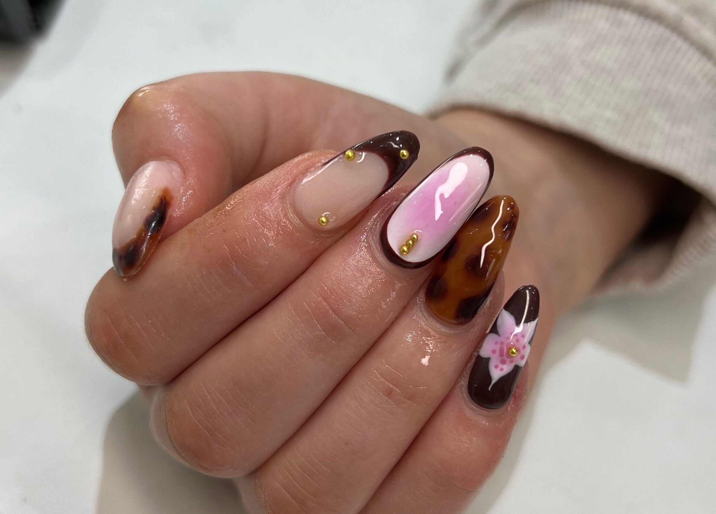 Intricate nail art at Nailedit Bymillie, Burnley, England, GB featuring brown and pink designs with floral accents.