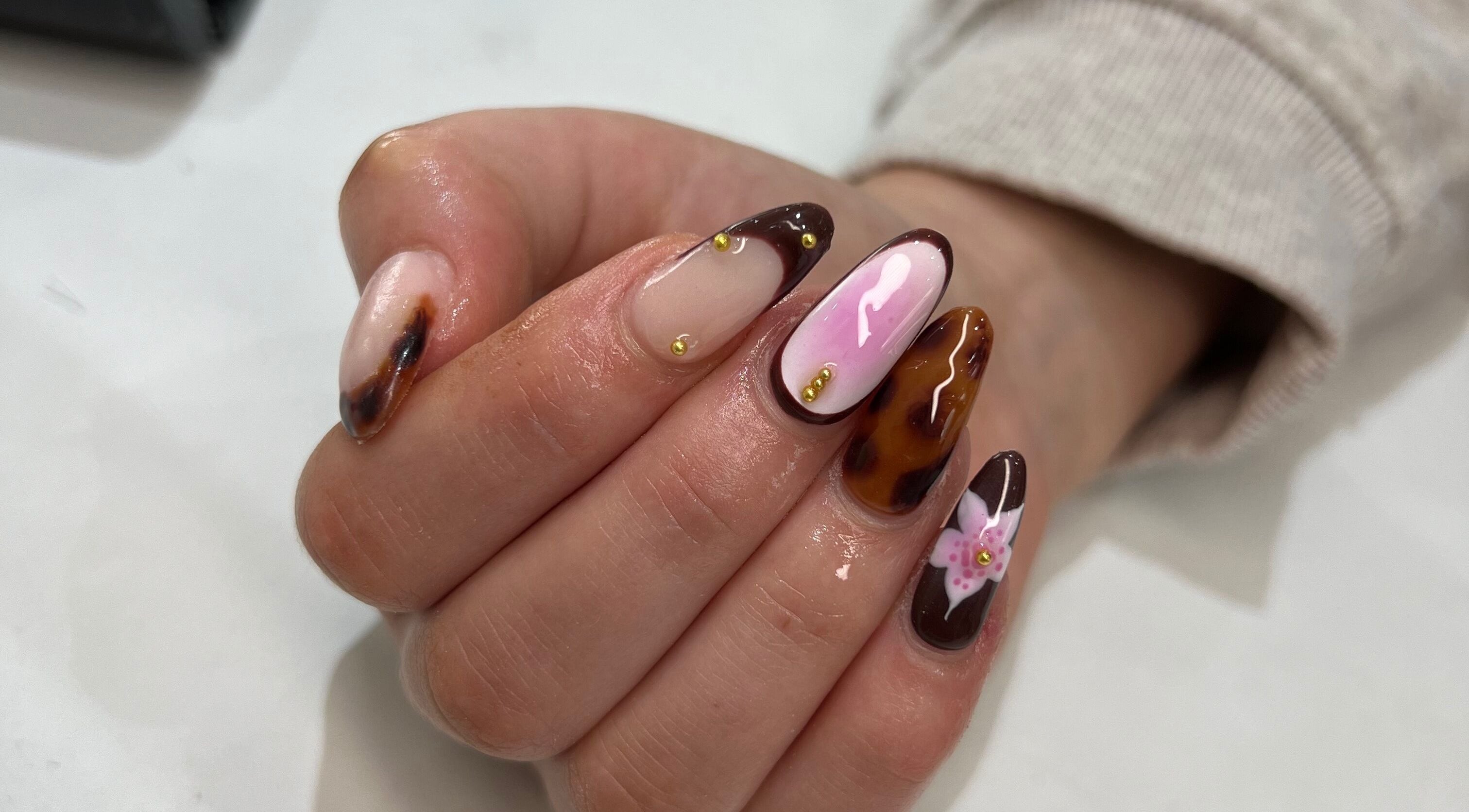 Intricate nail art at Nailedit Bymillie, Burnley, England, GB featuring brown and pink designs with floral accents.