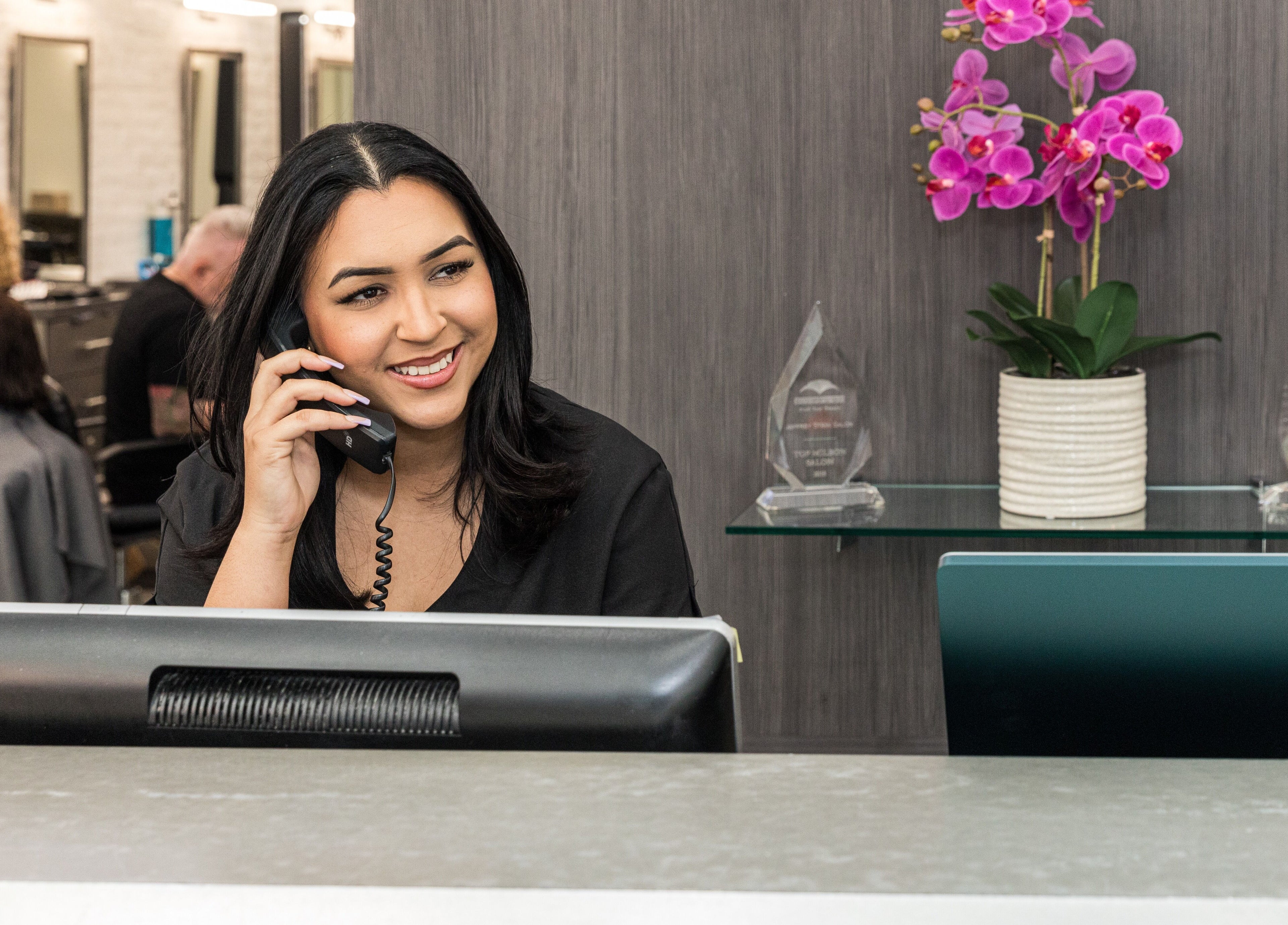 Receptionist at Jeffrey Stein Salon in New York, New York, US, smiling while answering a phone call.