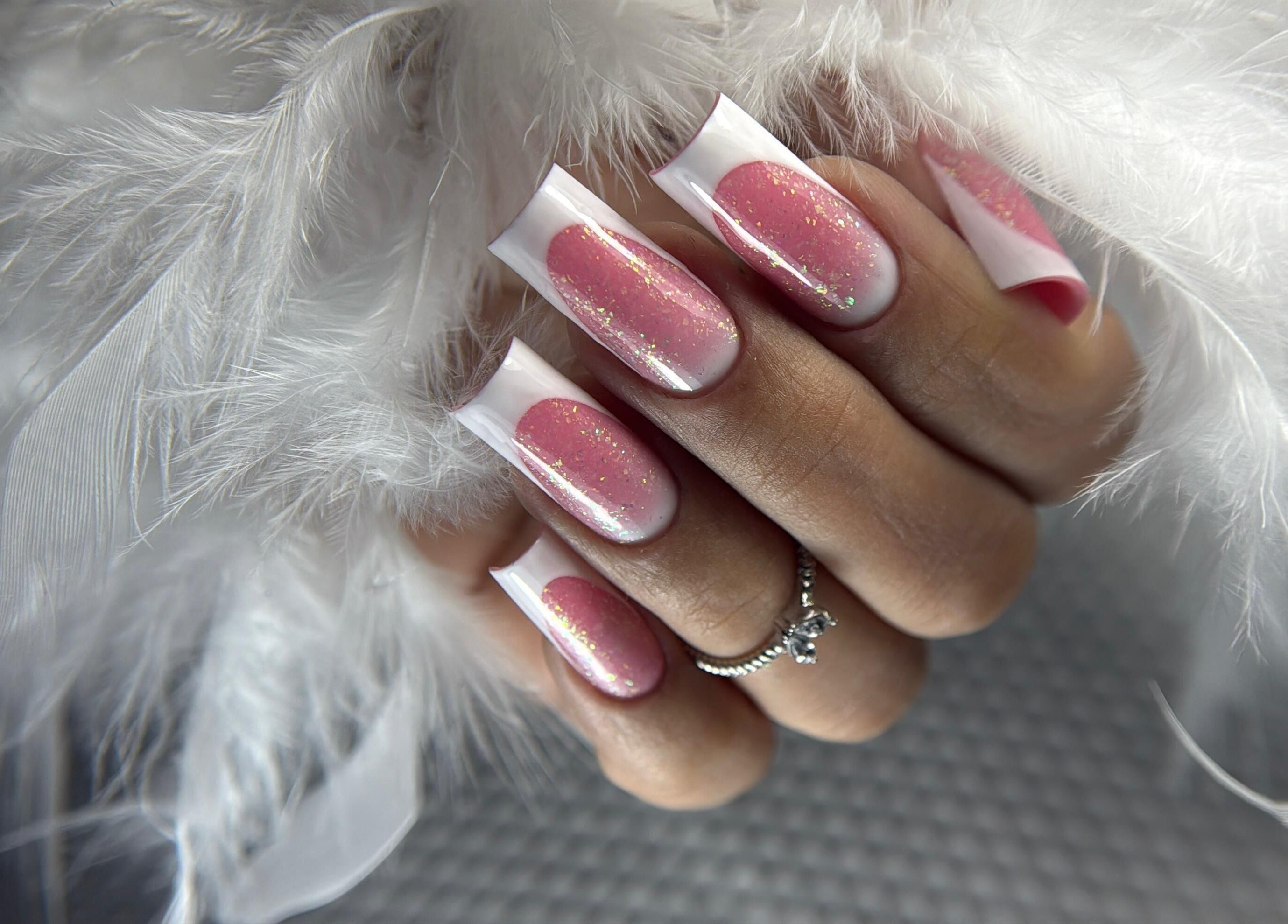 Diseño de uñas rosa brillante en DOKL, Surquillo, Provincia De Lima, PE, rodeado de plumas blancas.