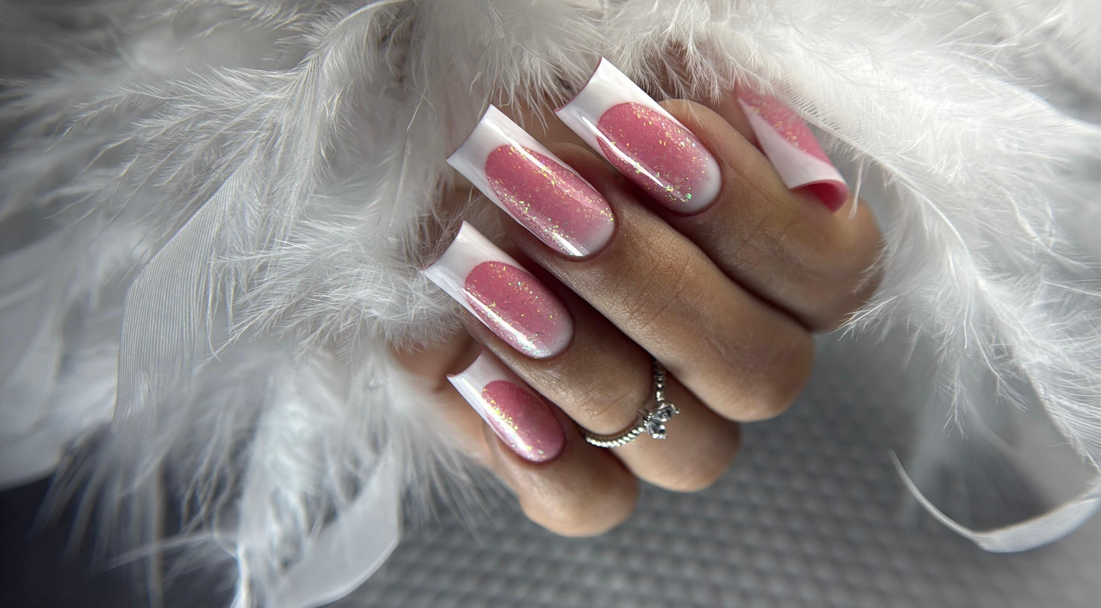 Diseño de uñas rosa brillante en DOKL, Surquillo, Provincia De Lima, PE, rodeado de plumas blancas.